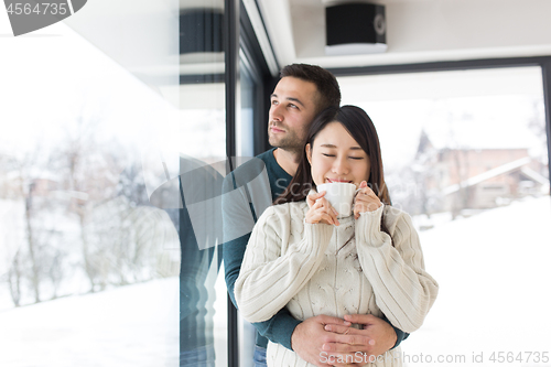 Image of multiethnic couple enjoying morning coffee by the window