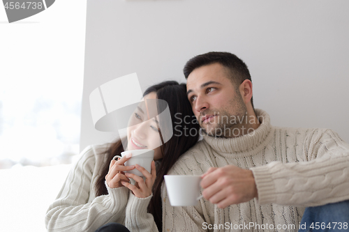 Image of multiethnic couple enjoying morning coffee by the window