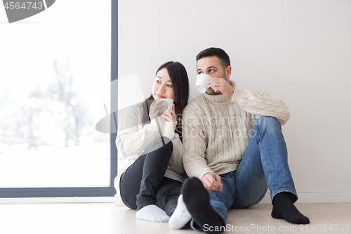 Image of multiethnic couple enjoying morning coffee by the window