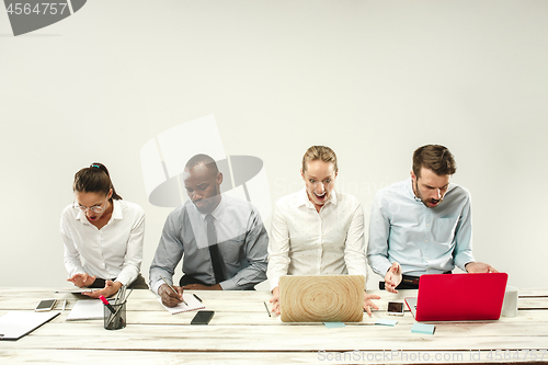 Image of Young men and women sitting at office and working on laptops. Emotions concept