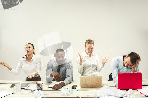 Image of Young men and women sitting at office and working on laptops. Emotions concept