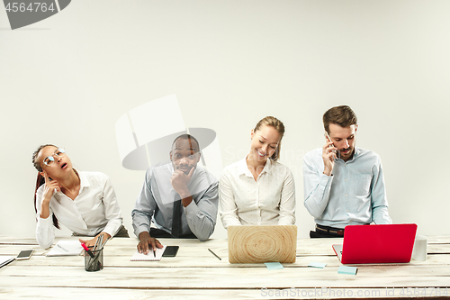 Image of Young men and women sitting at office and working on laptops. Emotions concept