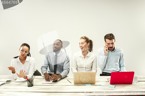 Image of Young men and women sitting at office and working on laptops. Emotions concept