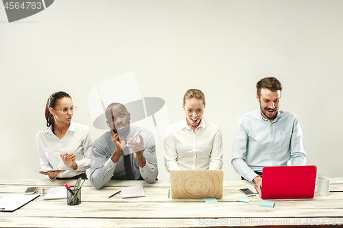 Image of Young men and women sitting at office and working on laptops. Emotions concept