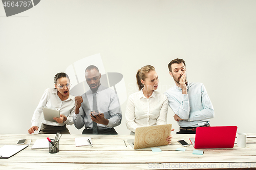 Image of Young men and women sitting at office and working on laptops. Emotions concept