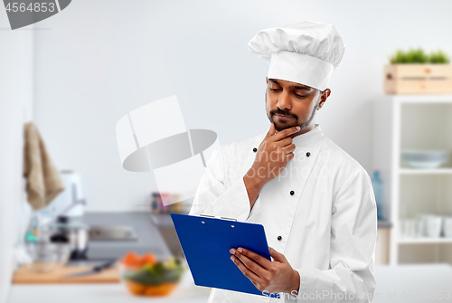 Image of indian chef reading menu on clipboard at kitchen