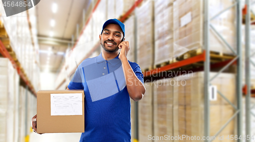 Image of delivery man with smartphone and box at warehouse