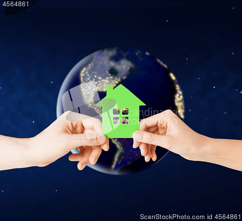 Image of hands holding green house over earth in space