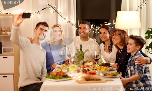 Image of family having dinner party and taking selfie