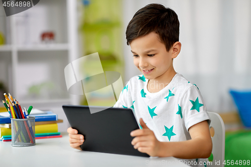 Image of student boy with tablet pc and notebook at home