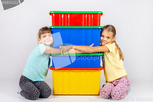 Image of Two girls hug big plastic boxes