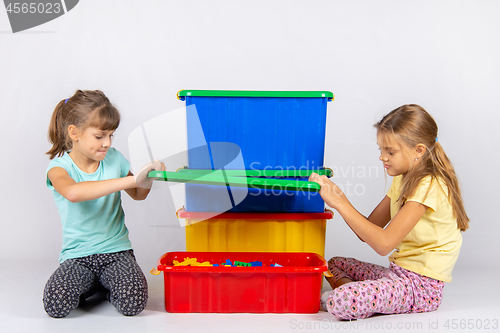 Image of Two girls opened a large plastic box with toys