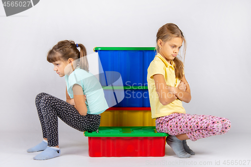 Image of Two girls quarreled, sit on a box and turned away from each other