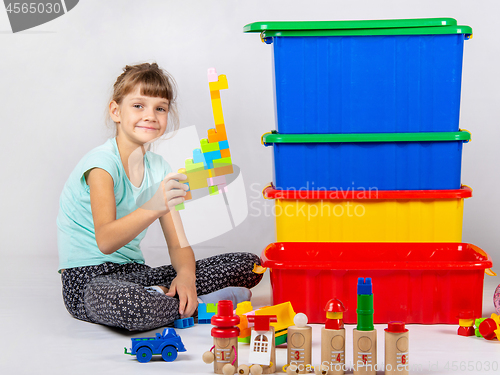 Image of Girl playing toys, large plastic boxes are standing nearby