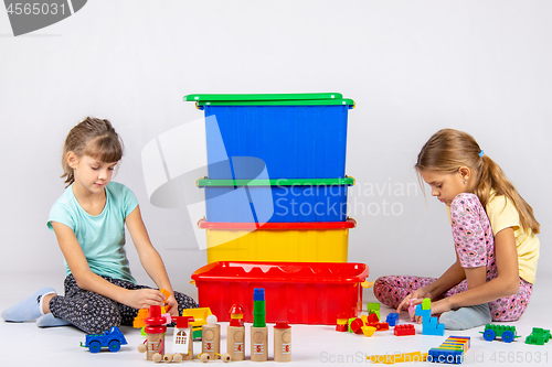 Image of Two girls play toys, in the middle are boxes with toys