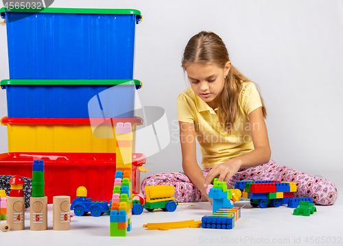 Image of Ten year old girl playing toys sitting on the floor