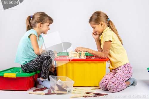 Image of Two girls collect a house on a box with toys