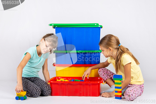 Image of Two girls opened a box with a designer and start to play toys