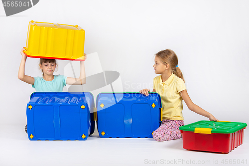 Image of Two girls play with large plastic boxes