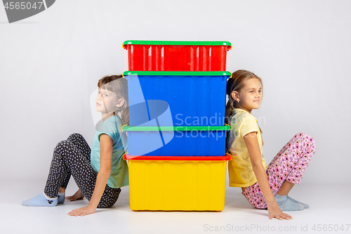 Image of Two girls from different sides leaned their backs on plastic boxes