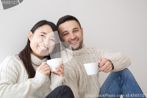 Image of multiethnic couple enjoying morning coffee by the window