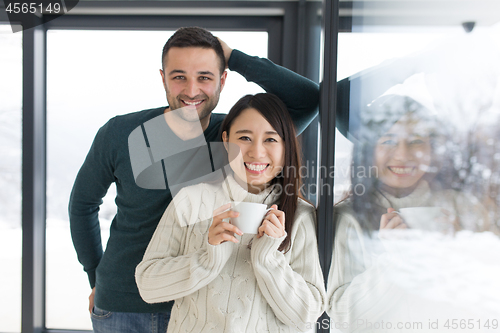 Image of multiethnic couple enjoying morning coffee by the window