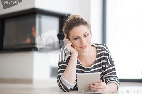 Image of woman using tablet computer in front of fireplace