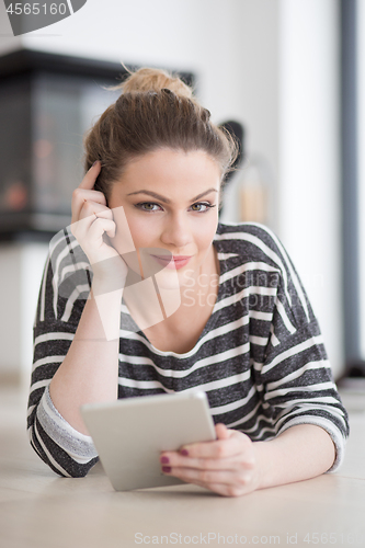 Image of woman using tablet computer in front of fireplace