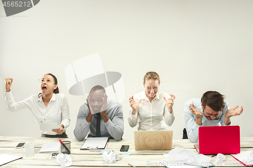 Image of Young men and women sitting at office and working on laptops. Emotions concept