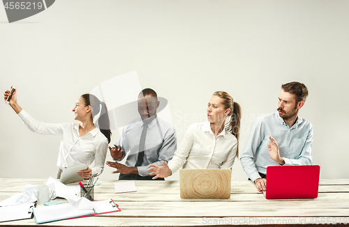 Image of Young men and women sitting at office and working on laptops. Emotions concept