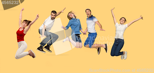 Image of Freedom in moving. young man and women jumping against yellow background