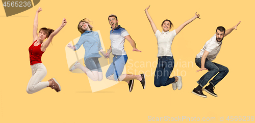 Image of Freedom in moving. young man and women jumping against yellow background