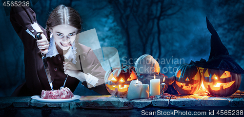 Image of Bloody Halloween theme: crazy girl with a knife and meat