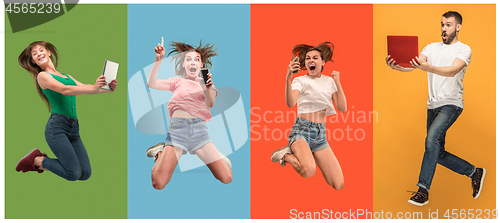 Image of The happy young jumping women and man with laptops and phone