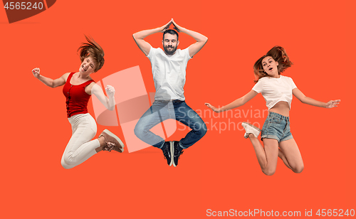 Image of Freedom in moving. young man and woman jumping against orange background