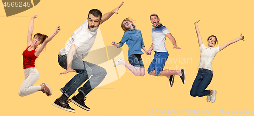 Image of Freedom in moving. young man and women jumping against yellow background