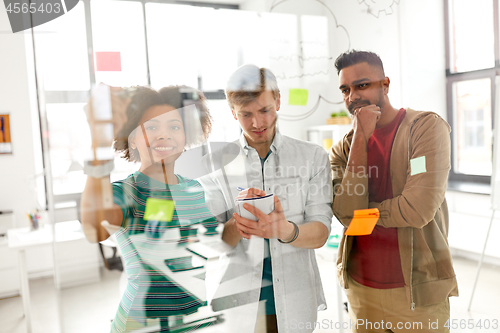 Image of happy creative team at office glass board