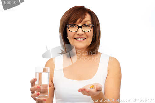 Image of senior woman with glass of water and pills