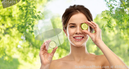 Image of smiling woman with cucumber over grey background