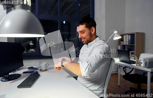 Image of happy businessman using smart watch at nigh office