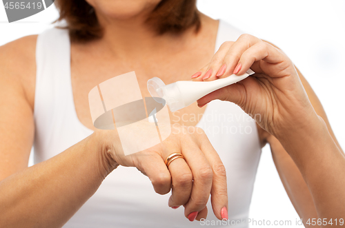 Image of close up of senior woman applying hand cream