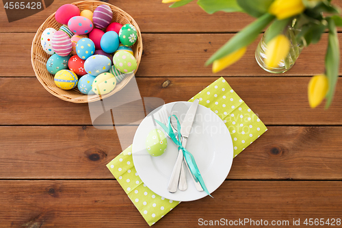 Image of easter eggs in basket, plates, cutlery and flowers