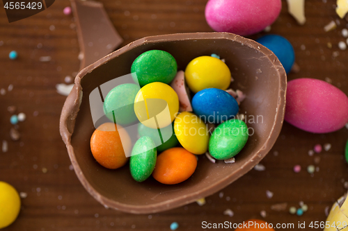 Image of chocolate egg and candy drops on wooden table