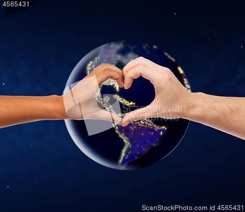 Image of hands showing heart gesture over earth in space