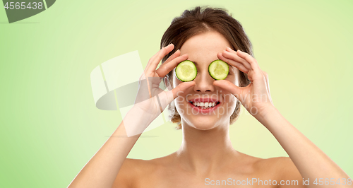 Image of smiling woman with cucumber over green background