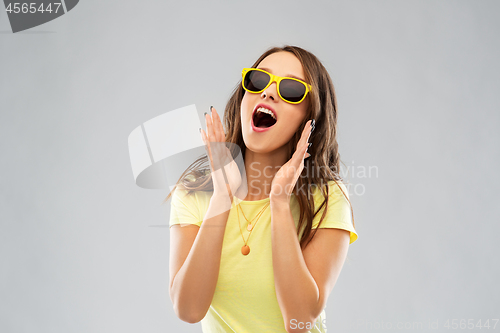 Image of amazed teenage girl in yellow sunglasses