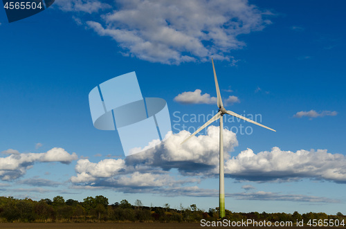 Image of Windmill by a blue sky with white clouds by fall season