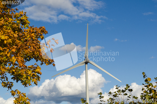 Image of Windmill by a blue sky and fall colored leaves