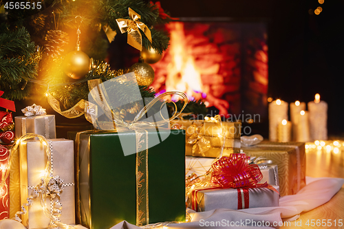 Image of Christmas presents and candles under Christmas tree