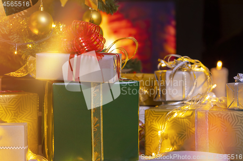 Image of Christmas presents and candles under Christmas tree